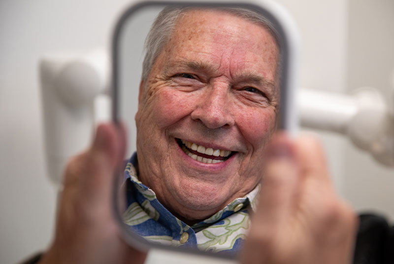 Patient smiling into mirror after dental implant procedure